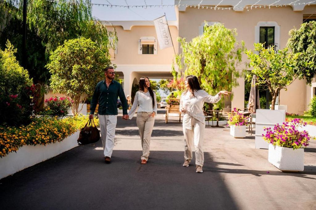 Un groupe de trois personnes marchant sur un trottoir dans l'établissement ananea Tropea Yachting Resort, à Tropea