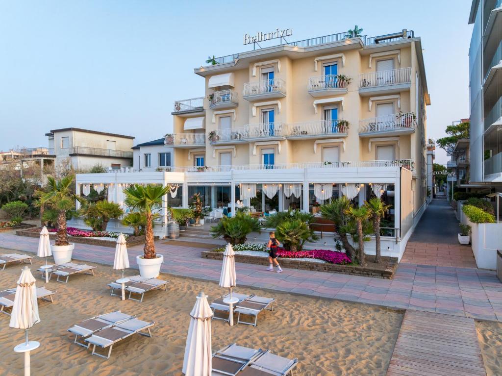 un hôtel avec des tables et des parasols devant lui dans l'établissement Hotel Bellariva, à Lido di Jesolo