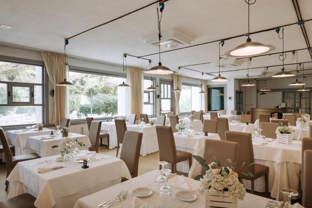 un restaurant avec des tables et des chaises blanches et des fenêtres dans l'établissement Grand Hotel la Chiusa di Chietri, à Alberobello
