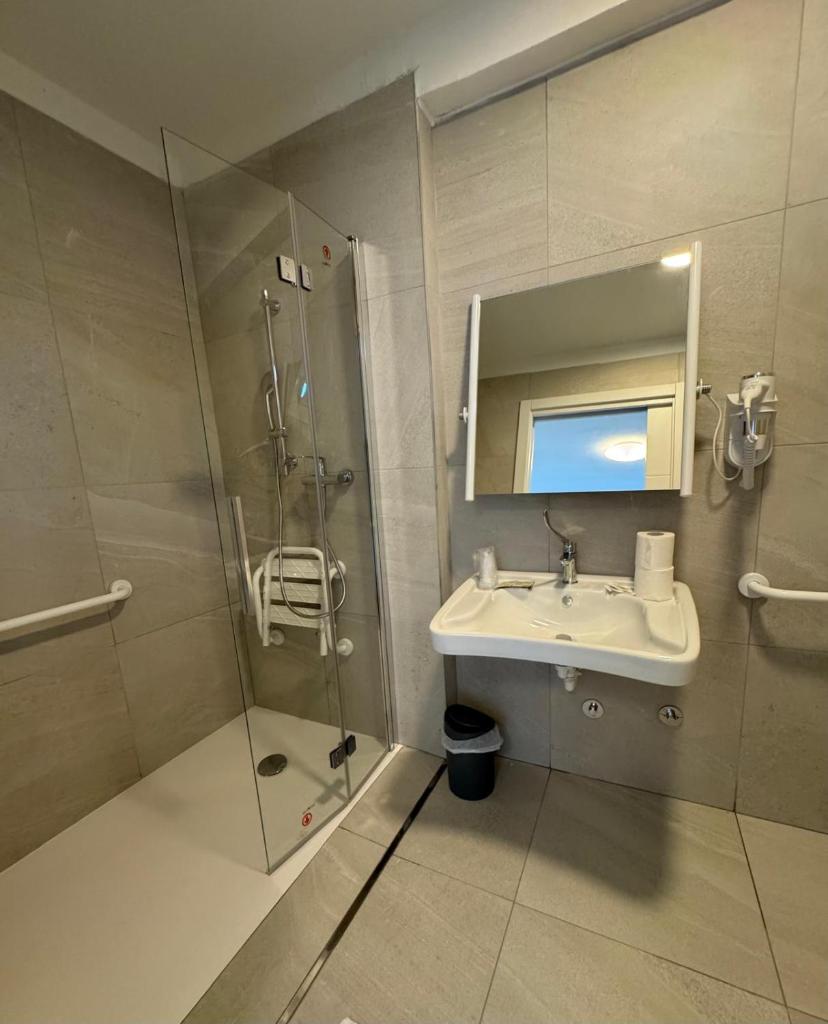 une salle de bain avec un lavabo et une douche avec un miroir dans l'établissement Hotel DOLCEVITA Park & Beach included, à Lido di Jesolo