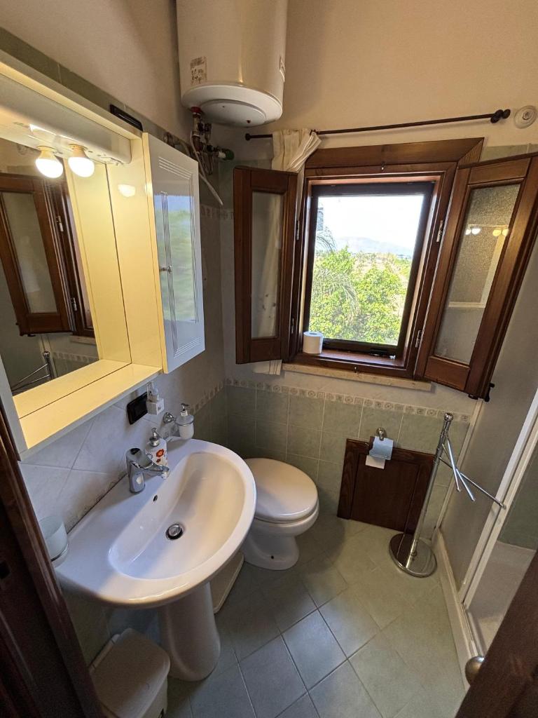 une salle de bain avec un lavabo et des toilettes et une fenêtre dans l'établissement Villa delle Cecilie, à Partinico