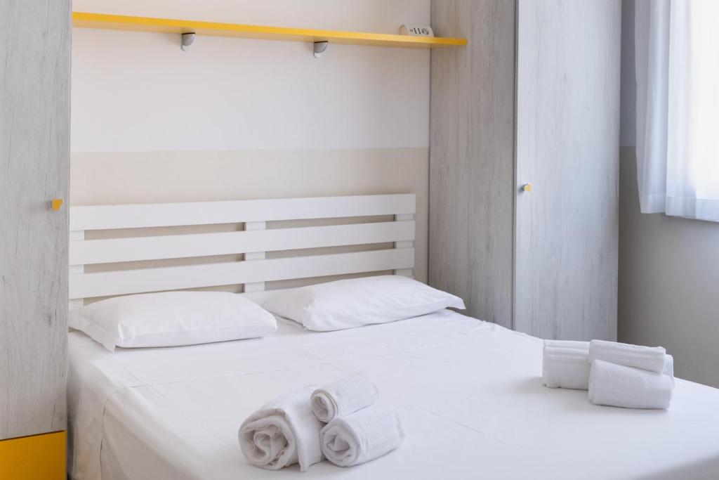 une chambre avec un lit blanc avec des serviettes dessus dans l'établissement Aurora Residence, à Lido Adriano