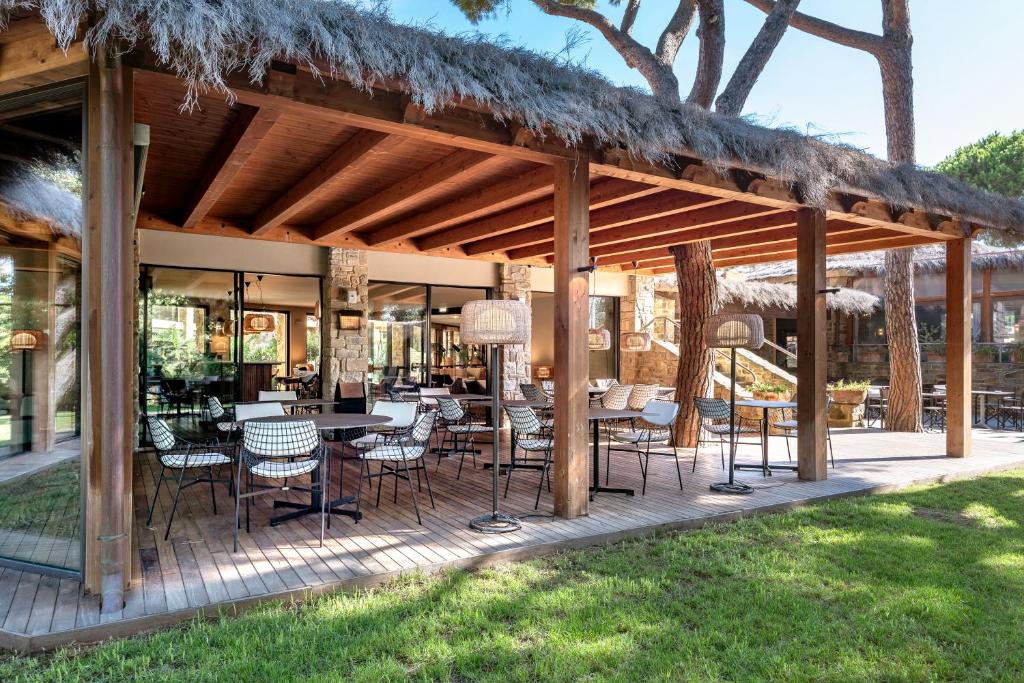 une terrasse en bois avec des tables et des chaises dessus dans l'établissement Roccamare Resort - Casa di Ponente, à Castiglione della Pescaia
