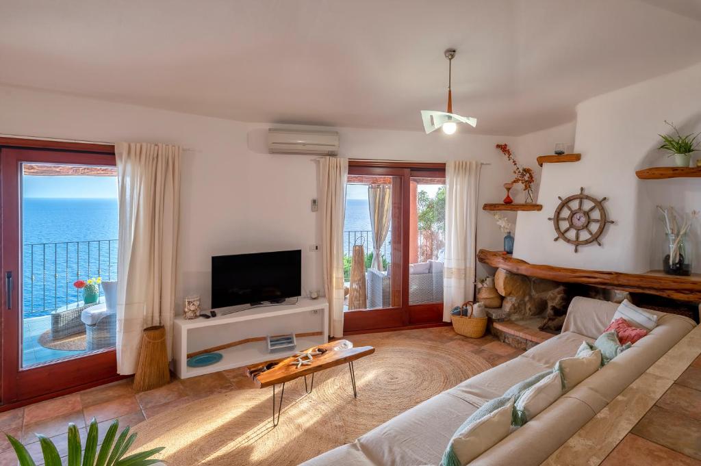 un salon avec un canapé et une télévision dans l'établissement Villa Patty with infinity pool in front of the sea, parking and wifi, à Torre delle Stelle