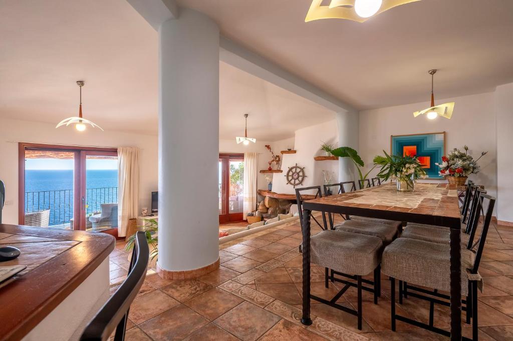 une salle à manger avec une table et des chaises et l'océan dans l'établissement Villa Patty with infinity pool in front of the sea, parking and wifi, à Torre delle Stelle