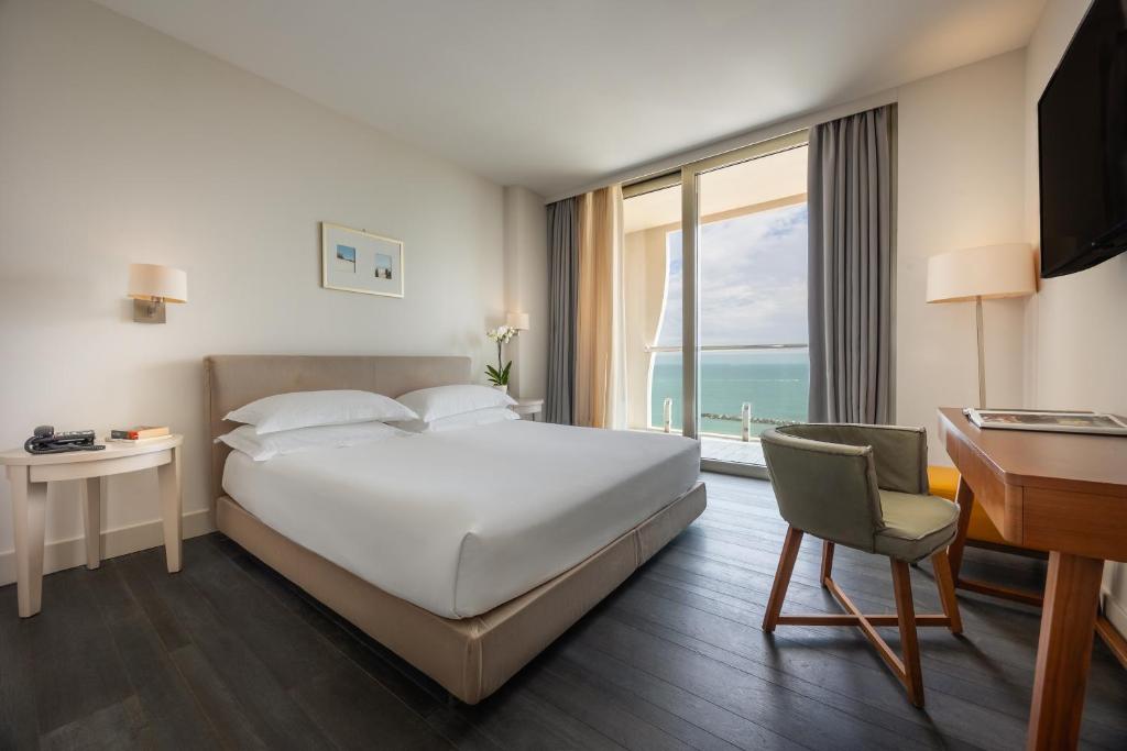 une chambre d'hôtel avec un lit, un bureau et une fenêtre dans l'établissement Excelsior Hotel, SPA & Lido - Preferred Hotels & Resorts, à Pesaro