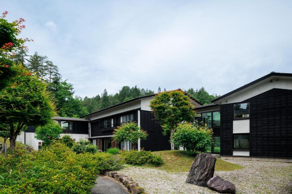 une maison noire avec un rocher devant elle dans l'établissement Hotel Kikori, à Hida