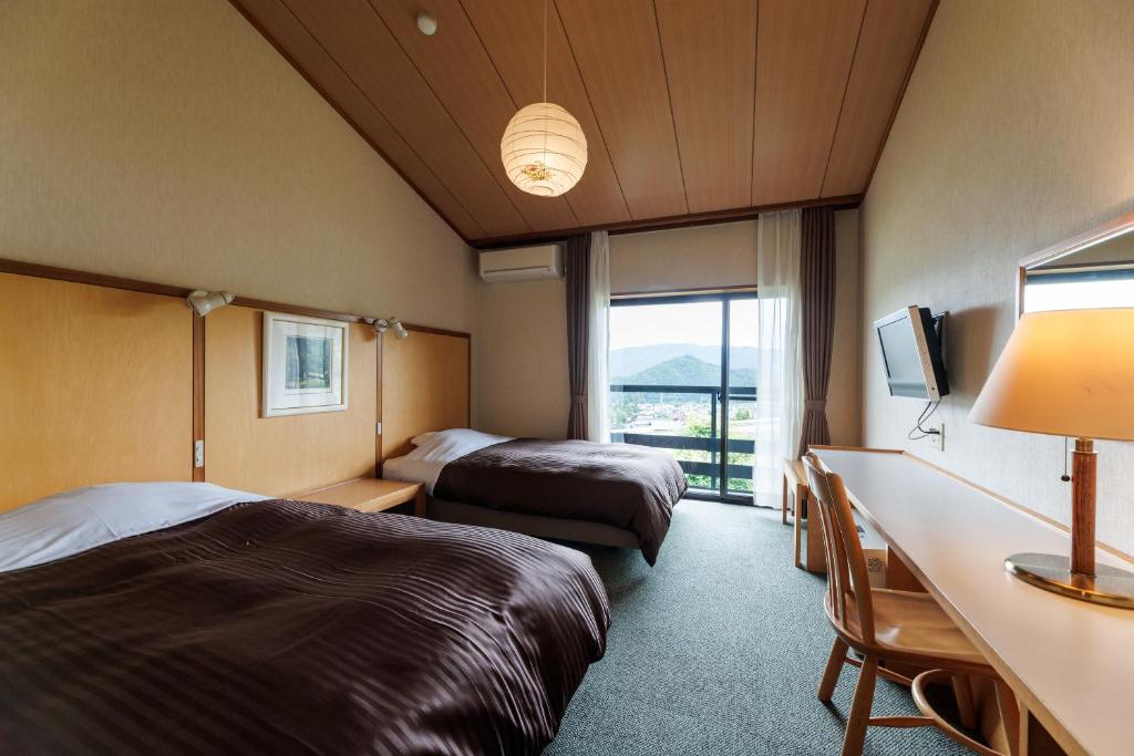 une chambre d'hôtel avec deux lits, un bureau et une fenêtre dans l'établissement Hotel Kikori, à Hida