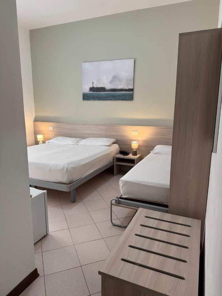 une chambre d'hôtel avec deux lits et une table dans l'établissement Hotel Ammare, à Sottomarina 6 autres photos