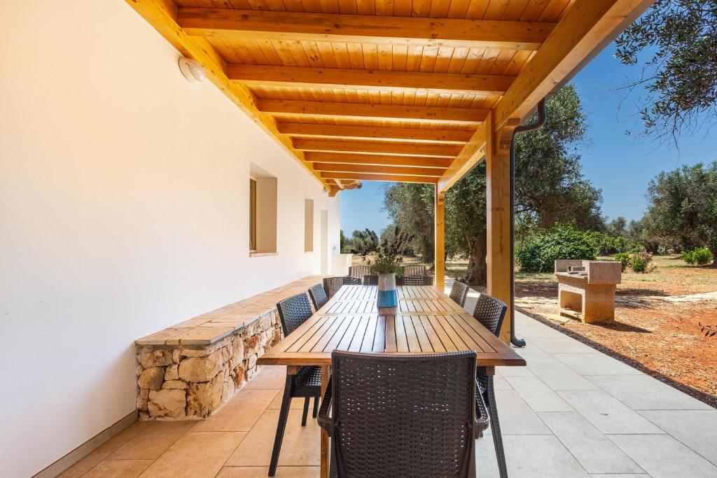 une table et des chaises en bois sur une terrasse dans l'établissement Trullo Fico by Perle di Puglia, à San Michele Salentino