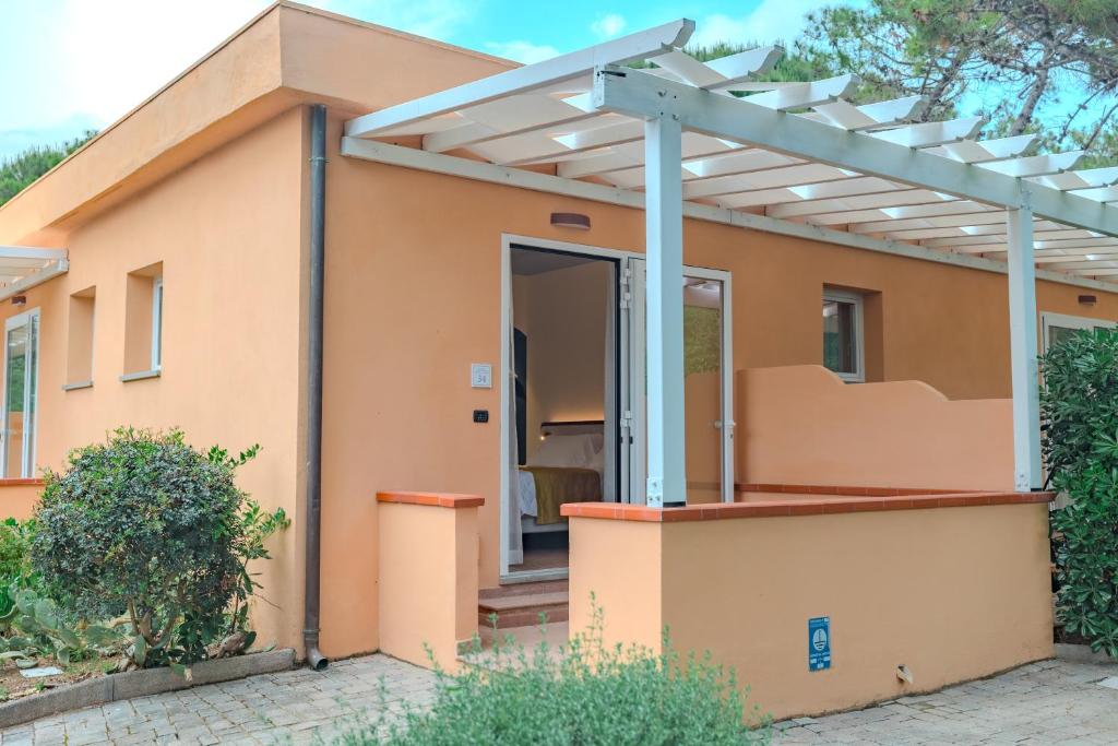 une maison avec une pergola devant elle dans l'établissement Tuscany Hotel Alle Dune, à Marina di Castagneto Carducci