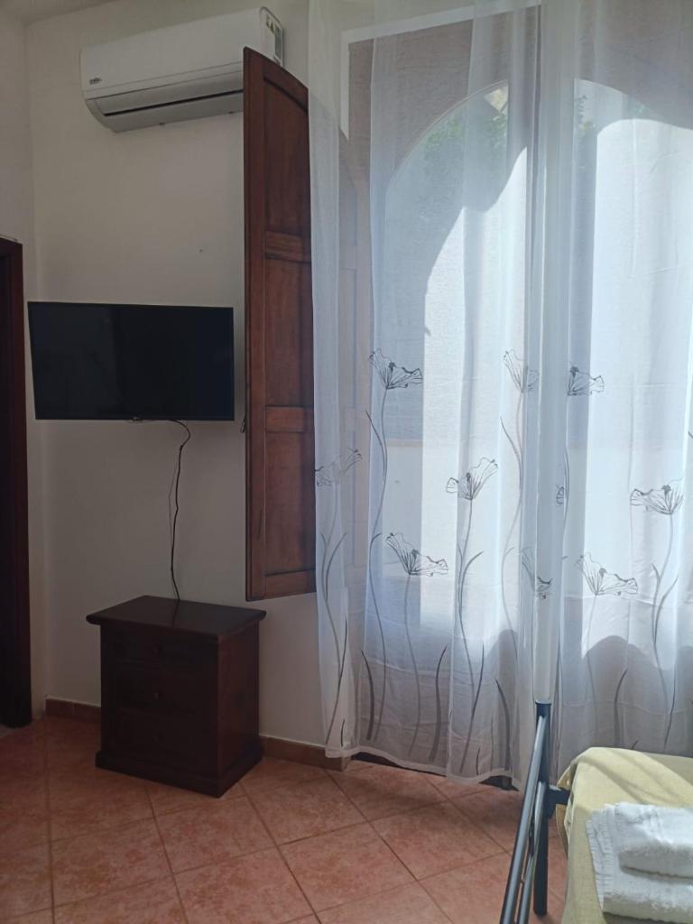- une chambre avec une télévision et une fenêtre avec un rideau dans l'établissement Albergo diffuso Borgo Gallodoro da Sara, à Gallodoro