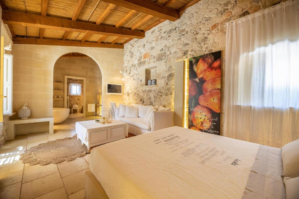 une chambre avec un lit et un salon dans l'établissement Masseria Blanca Lapis, à Martano