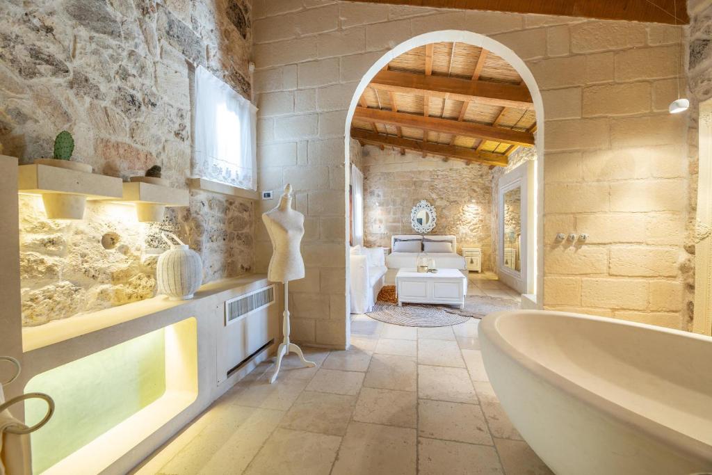 une salle de bain avec une grande baignoire dans un mur de pierre dans l'établissement Masseria Blanca Lapis, à Martano