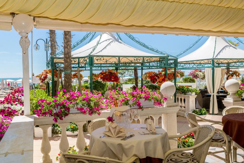 - une table blanche avec des fleurs dans un pavillon dans l'établissement Luxor e Cairo The Beach Resort, à Lido di Jesolo