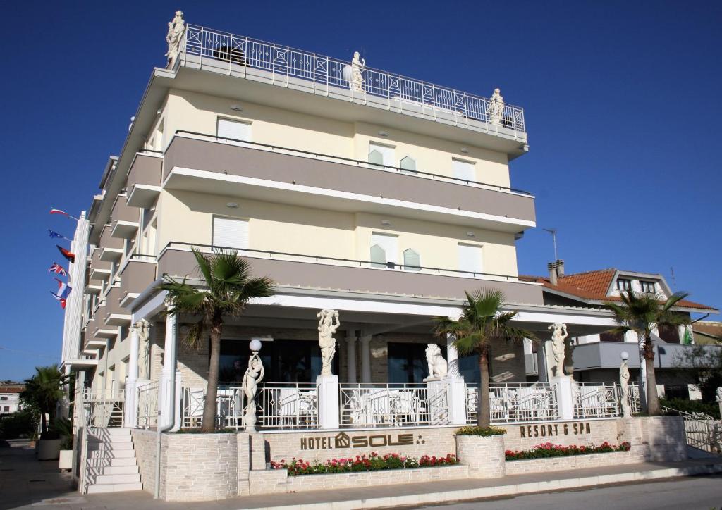 un grand bâtiment blanc avec des palmiers devant dans l'établissement GFH - Hotel Sole Resort & Spa, à Marotta