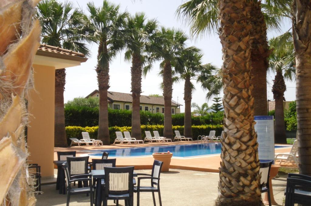 un complexe avec une piscine et des palmiers dans l'établissement Villa Laura Residence Hotel Apartments & Studios, à Ascea