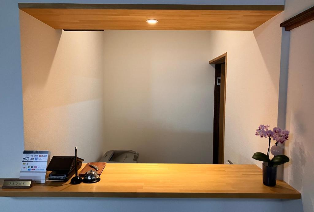 un bureau avec un bureau en bois avec un vase de fleurs dans l'établissement Yamakyuso, à Otari