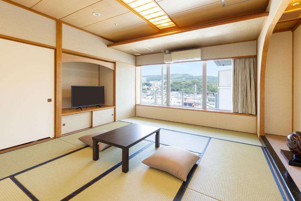 un salon avec une table et une télévision dans l'établissement Ooedo Onsen Monogatari Premium Ito Hotel New Okabe, à Itō