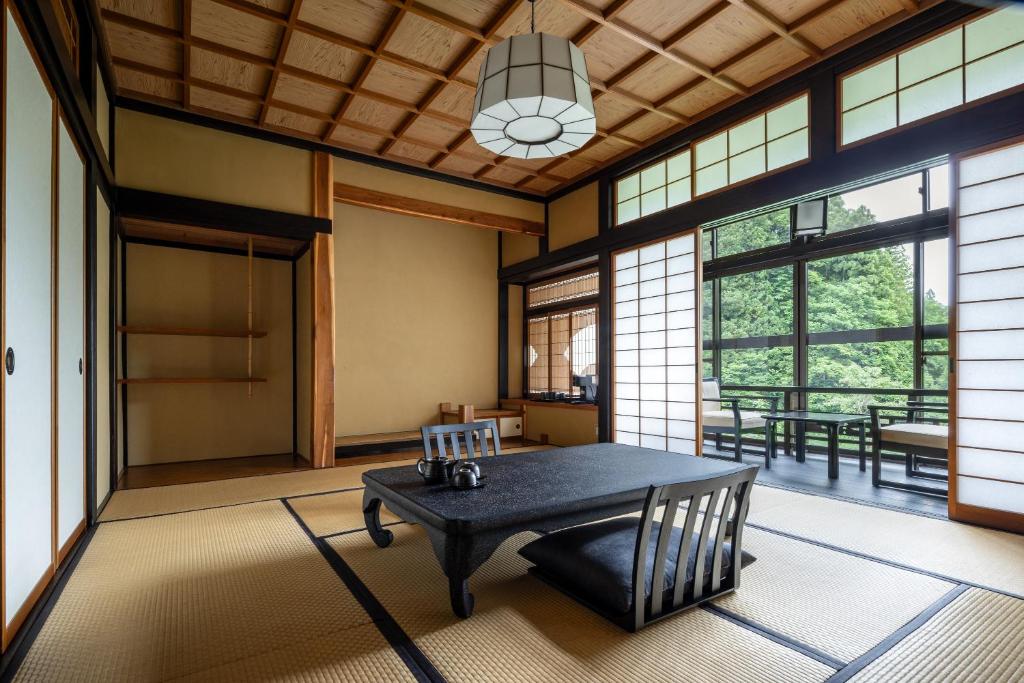 Cette grande chambre dispose d'une table, de chaises et de fenêtres. dans l'établissement Osawayama Onsen Osawakan, à Minami Uonuma