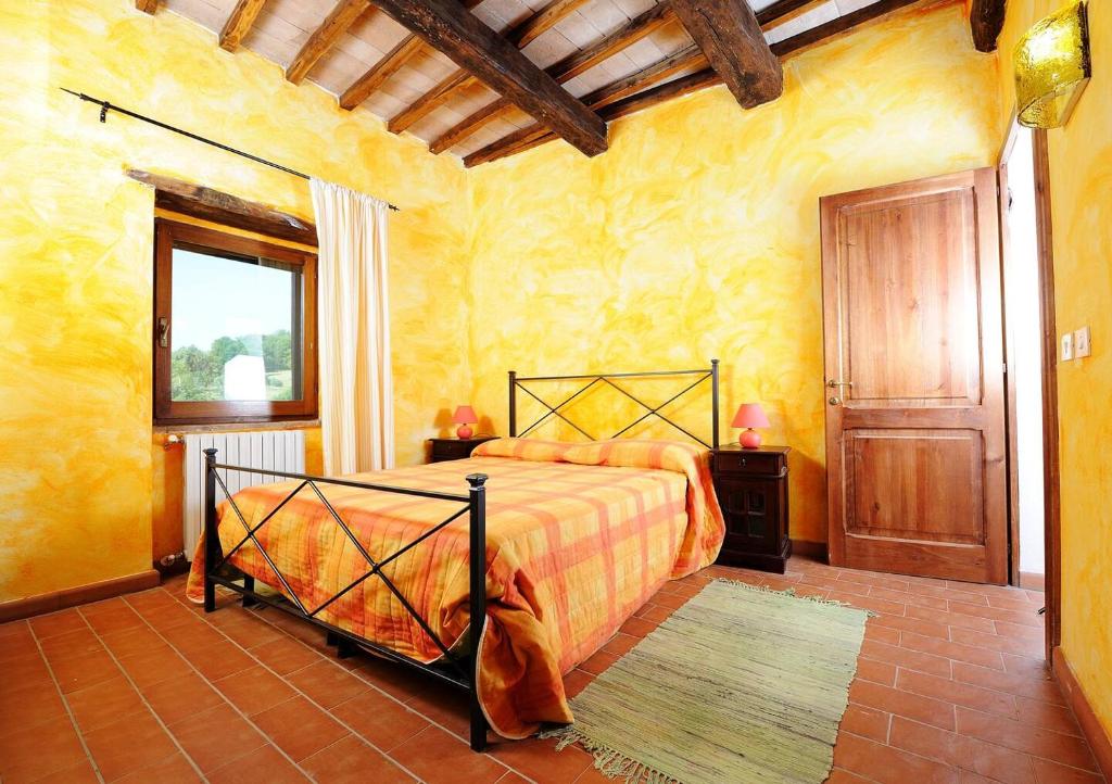 - une chambre avec un lit dans une pièce aux murs jaunes dans l'établissement Antico Casale in pietra con Piscina privata, à Monte Molino