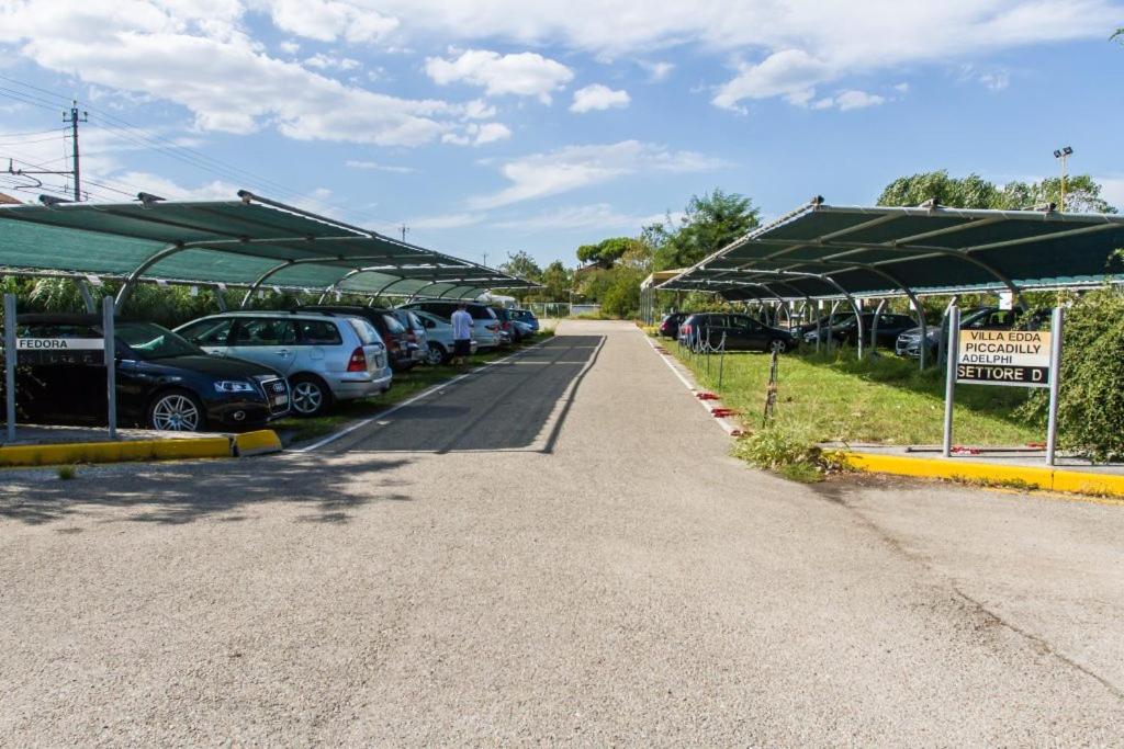 un parking avec des voitures garées sous des parasols verts dans l'établissement Hotel Consul - Family Hotel, à Riccione