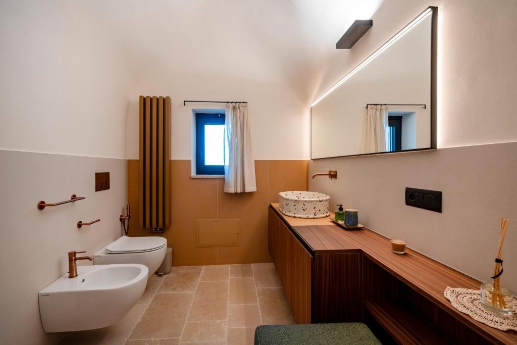 une salle de bain avec un lavabo, des toilettes et un miroir dans l'établissement Dimora Dormio, à Monopoli 14 autres photos