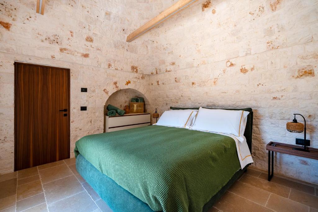 - une chambre avec un lit vert dans un mur en pierre dans l'établissement Dimora Dormio, à Monopoli