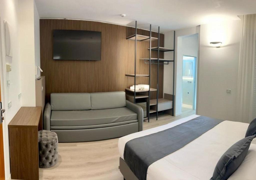 une chambre avec un lit, un canapé et une télévision dans l'établissement Hotel Poker, à Riccione