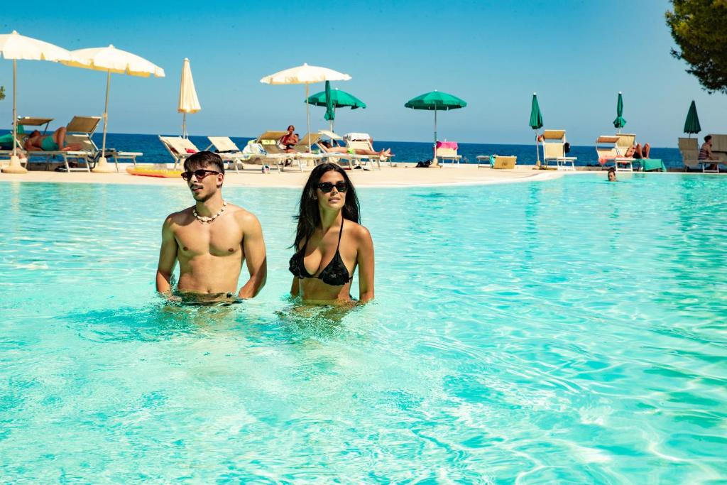 un homme et une femme dans l'eau d'un complexe dans l'établissement Club Hotel Marina Seada Beach, à Budoni