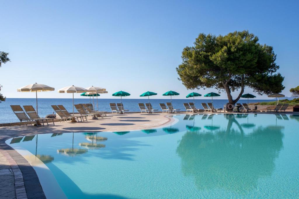 une piscine avec chaises et parasols sur la plage dans l'établissement Club Hotel Marina Seada Beach, à Budoni