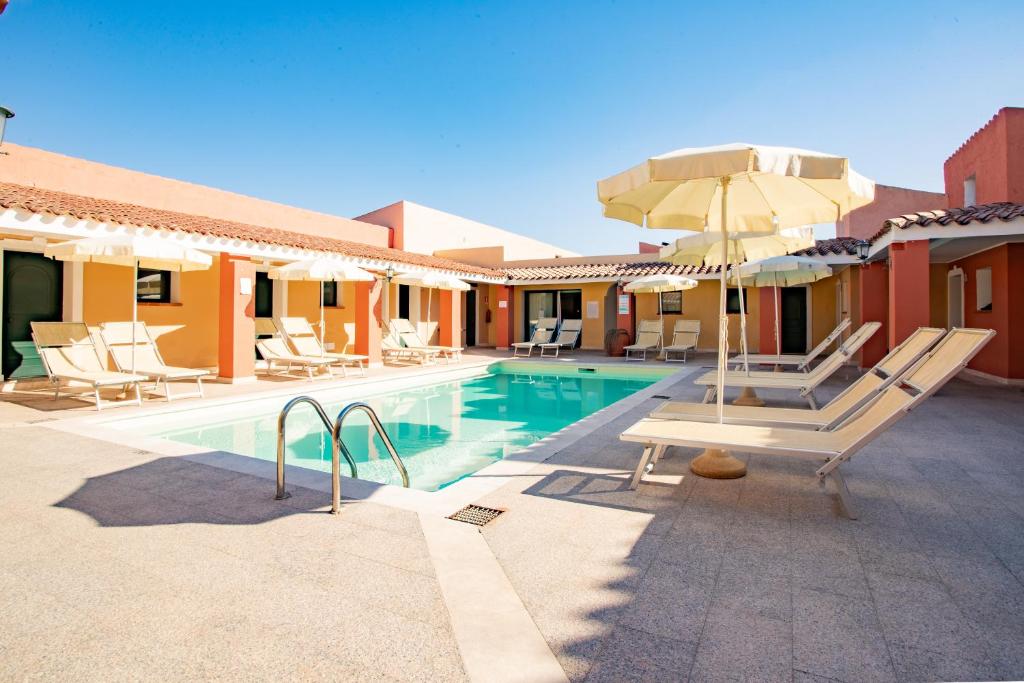 une piscine avec des chaises et un parasol à côté d'une maison dans l'établissement Club Hotel Marina Seada Beach, à Budoni