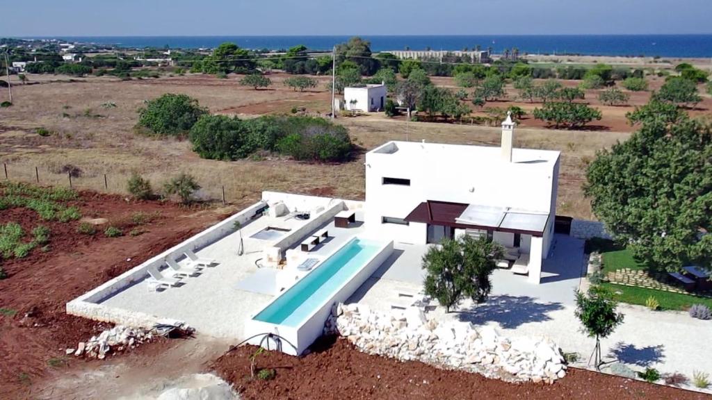 une vue aérienne d'une maison blanche avec piscine dans l'établissement Aeneas Villa Pool & Jacuzzi al mare Torre Guaceto, à Specchiolla