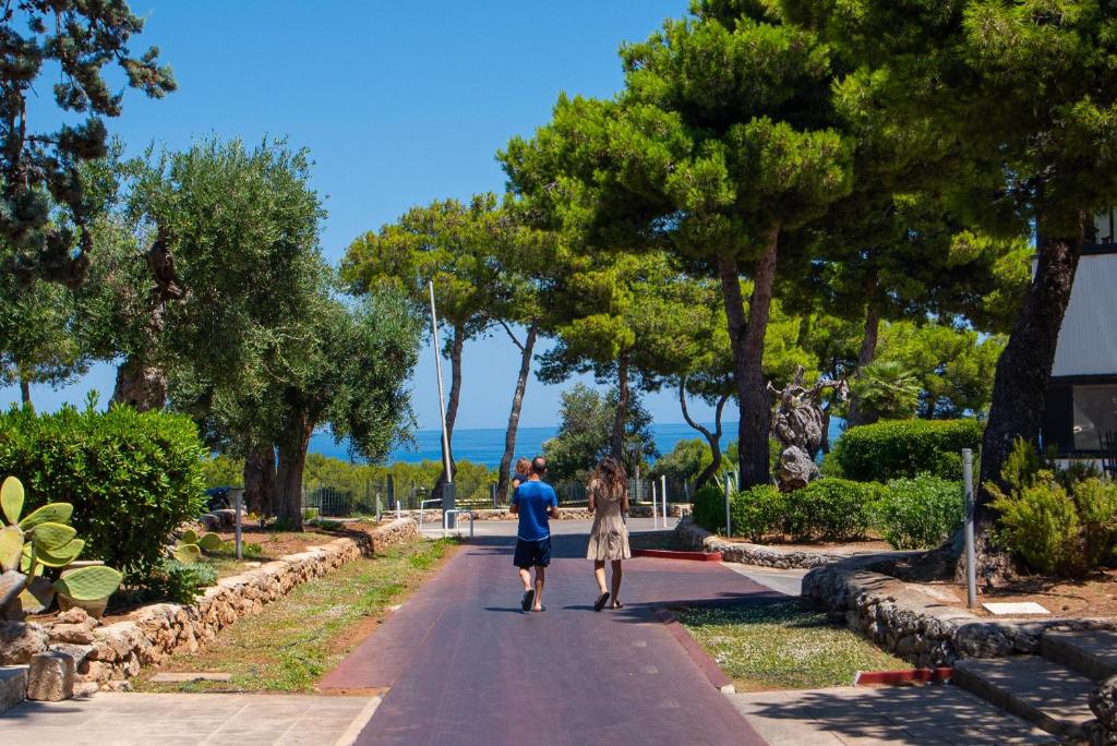deux personnes marchant sur une route dans un parc dans l'établissement Porto Giardino - CDSHotels, à Monopoli