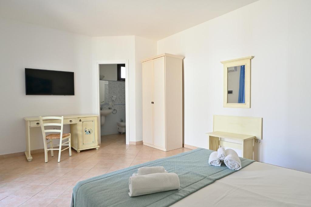 une chambre blanche avec un lit et un bureau dans l'établissement Baia delle Mimose Hotel, à Codaruina