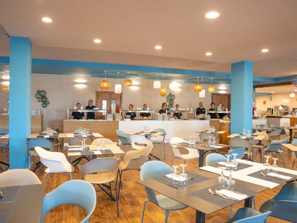 un restaurant avec des tables et des chaises et des gens en arrière-plan dans l'établissement Baia delle Mimose Hotel, à Codaruina