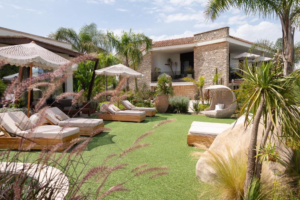 un jardin avec des chaises longues et des parasols en face d'une maison dans l'établissement Villa Flora, à Depressa