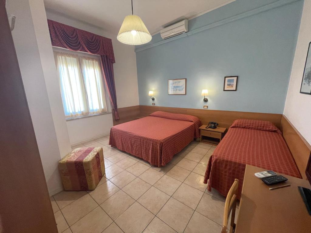 une chambre d'hôtel avec deux lits et une table dans l'établissement Hotel Amelia, à Fano