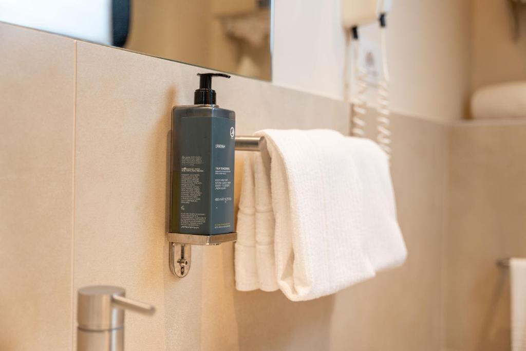 une bouteille de savon sur un porte-serviettes dans une salle de bain dans l'établissement Hotel 900, à Giulianova