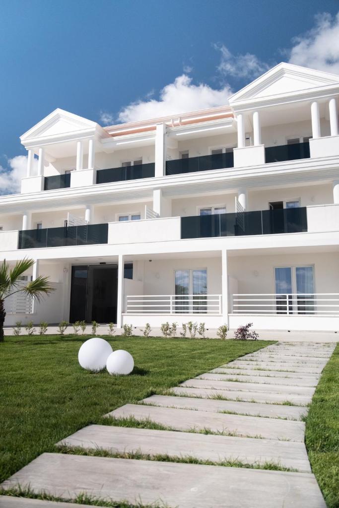 un grand bâtiment blanc avec une pelouse devant lui dans l'établissement Hotel Diadema, à Diamante