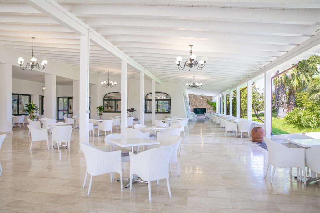 une salle à manger avec des tables blanches et des chaises blanches dans l'établissement Club Hotel Marina Beach, à Orosei