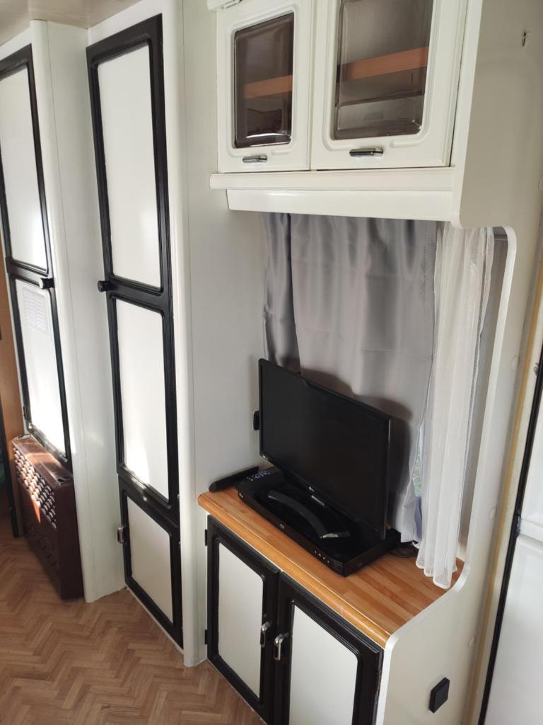 une télévision sur une table dans une pièce avec des fenêtres dans l'établissement Caravane avec spa privatif en campagne, à Apremont