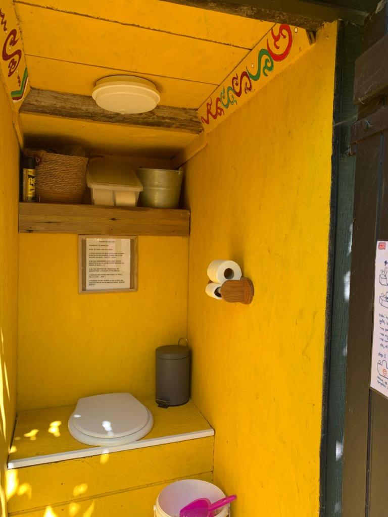 La salle de bains est pourvue de toilettes dans un mur jaune. dans l'établissement la yourte du moulin, à Champrond