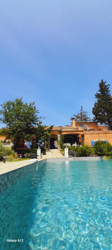 une grande piscine d'eau bleue devant une maison dans l'établissement GITE 2 personnes avec piscine, à Le Bosc
