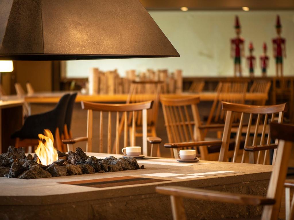 une table avec un feu dans un restaurant avec des chaises dans l'établissement Jozankei Manseikaku Hotel Milione, à Jozankei