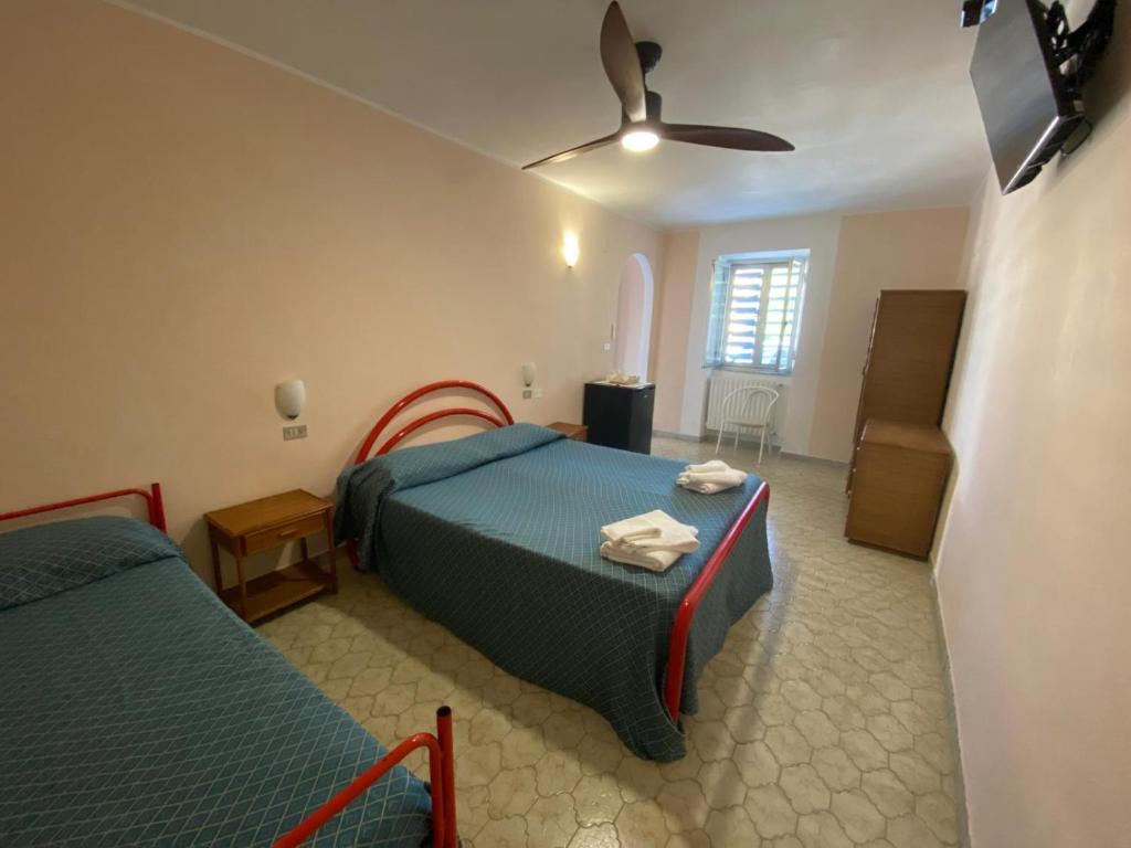 une chambre avec deux lits et un ventilateur de plafond dans l'établissement Cinquestelle Albergo del centro storico, à Palinuro