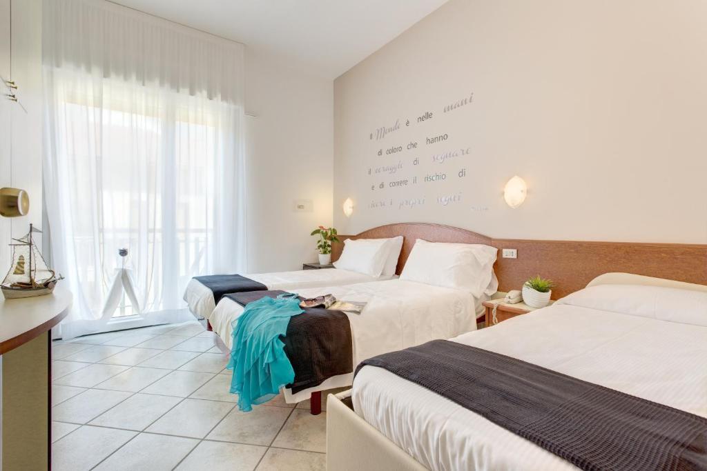 une chambre d'hôtel avec trois lits et une fenêtre dans l'établissement B&B Isabella, à Milano Marittima