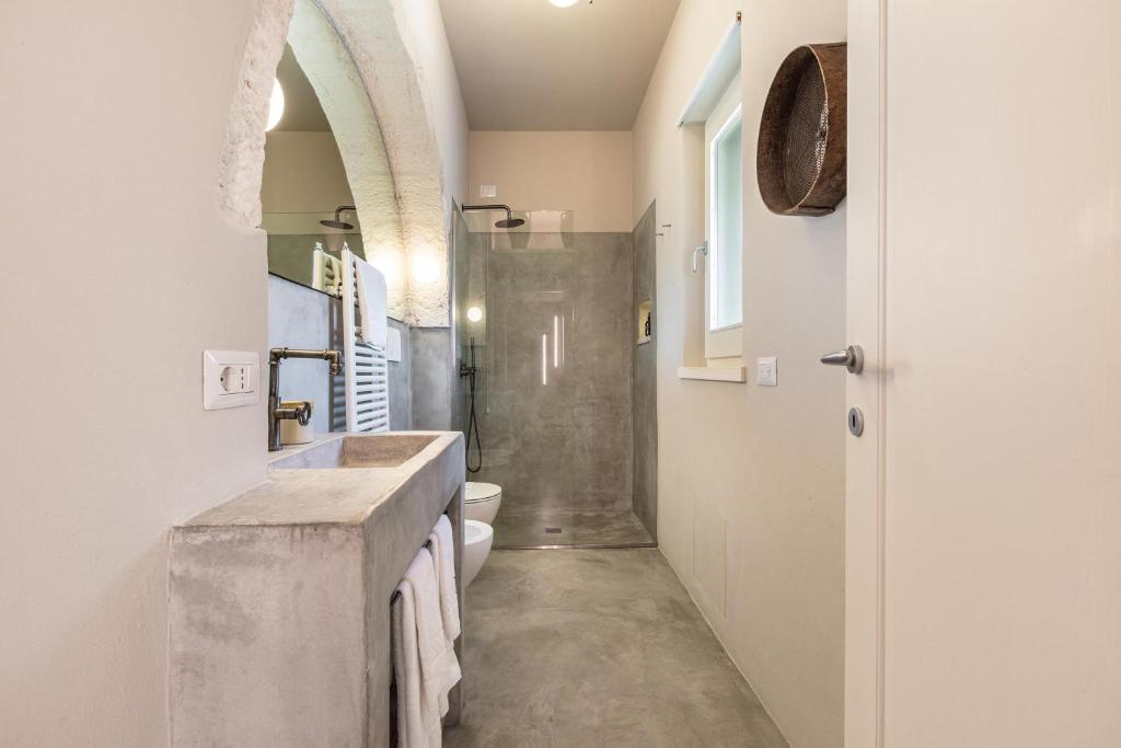 une salle de bain avec un lavabo et des toilettes dans l'établissement Trulli Almaviva by Perle di Puglia, à Cisternino