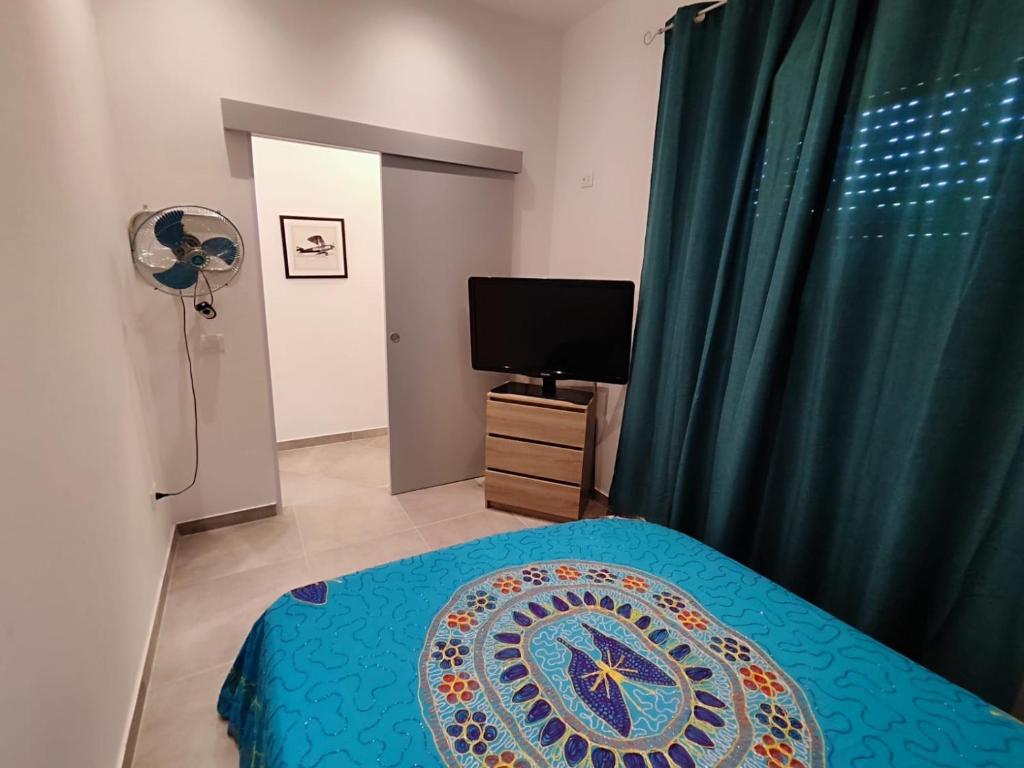 une chambre avec un lit et une télévision et un rideau vert dans l'établissement Puffolandia House, à Contrada Maeggio