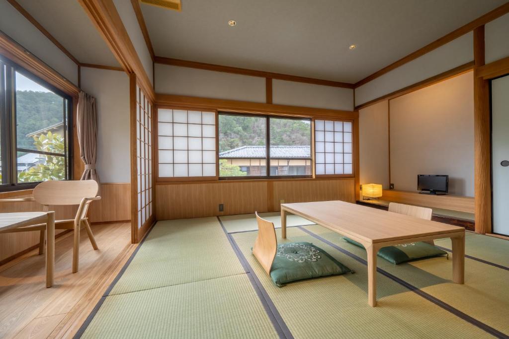 une pièce avec une table, des chaises et des fenêtres dans l'établissement Ryokan Yamazaki, à Kyoto